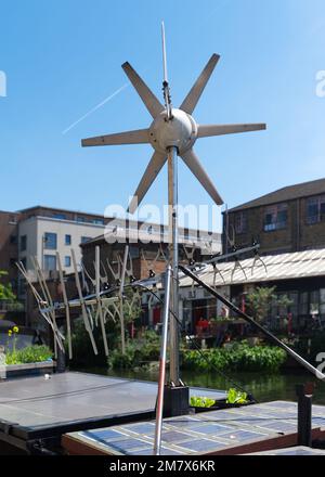 Windturbine und Sonnenkollektoren auf einem schmalen Boot, das auf einem Kanal festgemacht ist. East End, London Stockfoto