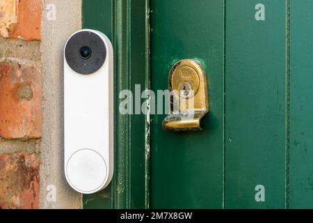 Eine Google Nest Video-Türklingel an einer grünen Tür mit einem Messing-Yale-Schloss, Großbritannien, Großbritannien Stockfoto