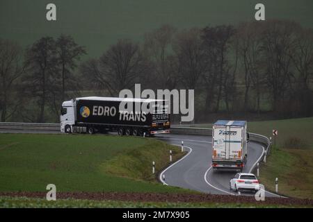 Scheden, Deutschland. 11. Januar 2023. Lastwagen umgehen die geschlossene Autobahn 7 auf einer Landstraße. Der Highway 7 im Süden Niedersachsens ist seit Montagabend geschlossen. Da ein Fahrzeug eine Substanz verloren hat, von der angenommen wird, dass es sich um Kerosin handelt, muss ein 60 km langer Abschnitt gründlich gereinigt werden. Kredit: Swen Pförtner/dpa/Alamy Live News Stockfoto