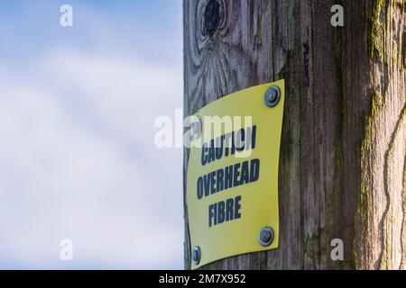 Schild auf einem hölzernen Telefonmast mit Warnung vor Glasfaserkabel für ländliche Breitbandverbindungen, County Down, Nordirland, Vereinigtes Königreich, Vereinigtes Königreich Stockfoto