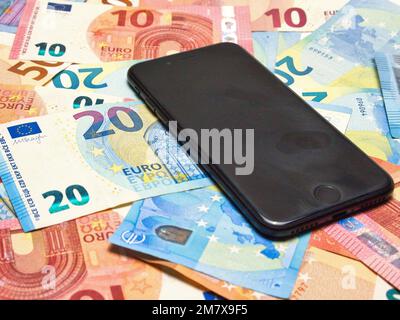 Ein Mobiltelefon, das auf verschiedenen Euro-Rechnungen steht, mit einem Schwerpunkt Stockfoto