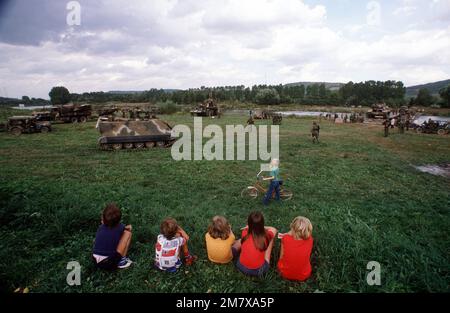 USA Gepanzerte Armeefahrzeuge, M-113 gepanzerte Personaltransporter, Jeeps, M551 Sheridan-Panzer bereiten sich auf eine Flussüberquerung auf einer Pontonbrücke vor, während deutsche Kinder zusehen. Die Armee nimmt an der REFORGER '82 Teil, der multinationalen Militärübung. Exaktes Datum Aufnahme Unbekannt. Betreff Betrieb/Serie: REFORGER '82 Land: Deutschland / Deutschland (DEU) Stockfoto