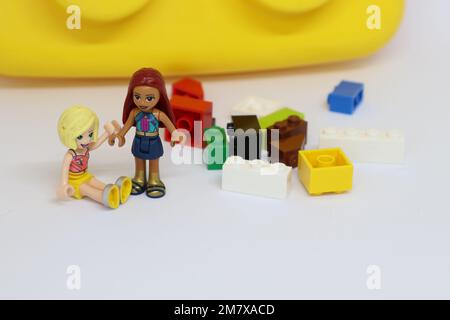 lego-Minifiguren neben einem Stapel lego-Bausteine mit einem großen Baustein im Hintergrund Stockfoto