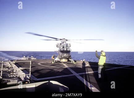 Ein Besatzungsmitglied signalisiert bei der Landung auf einem Schiff der Unitas XXI als SH-2F Seasprite light Airborne Multipurpose System (LAMPEN) Helikopter. Der Hubschrauber ist am Light Helicopter Anti-U-Boot-Geschwader 34 (HAL-34) befestigt. Betreff Betrieb/Serie: UNITAS XXI Land: Pazifik (POC) Stockfoto