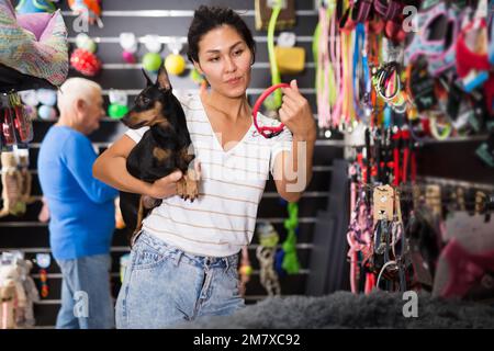 Asiatische Frau mit Hund Auswahl Kragen im Tiergeschäft Stockfoto