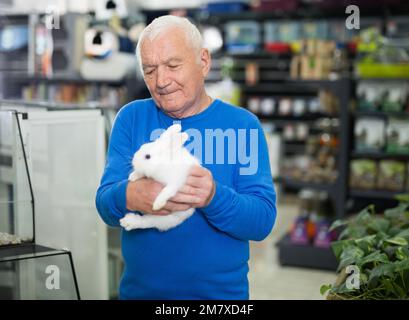 Porträt eines Mannes, der ein neues Haustier im Laden wählt und ein niedliches Kaninchen hält Stockfoto