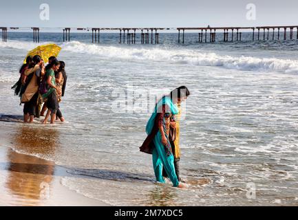 Allepey, Indien - 6. September 2012. Viele indische Touristen kommen zum Strand, um zu spazieren oder zu schwimmen. Eine von ihnen erscheint, als eine Welle ihre Füße befeuchtet Stockfoto