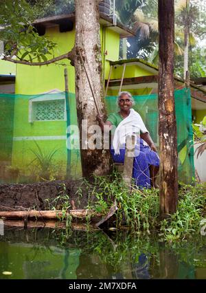 Allepey, Indien - 7. September 2012. Eine indische Frau beim Angeln mit einer Angelrute in den Kanälen von Alappuzha lächelt Touristen und Besuchern Stockfoto