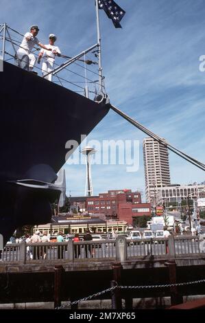 Zwei Crewmitglieder stehen am Steuerbordbug des geführten Raketenkreuzers USS LEAHY (CG-16), im Hafen während der Seemesse 1982. Im Hintergrund ist die Space Needle zu sehen. Basis: Seattle Staat: Washington (WA) Land: Vereinigte Staaten von Amerika (USA) Stockfoto