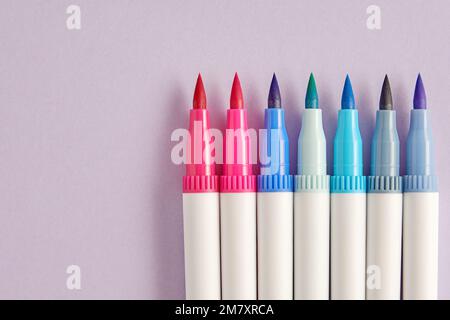 Pastellfarbene Aquarellmarkierungen zum Skizzieren isoliert auf violettem Hintergrund geöffnet. Malen und Kunst Hobby-Thema. Platz für Text kopieren Stockfoto
