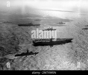 Steuerbordseitenansicht des nuklearbetriebenen Flugzeugträgers USS ENTERPRISE (CVN-65) und des Flugzeugträgers USS MIDWAY (CV-41) im Hintergrund, in deren Aufgabengruppen sie sich befinden. Die Fregatte USS HEPBURN (FF-1055) ist im Vordergrund. Land: Pazifik (POC) Stockfoto