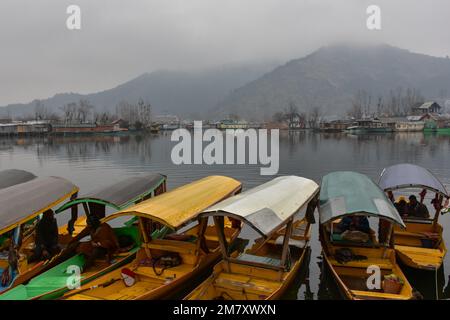 Srinagar, Indien. 11. Januar 2023. Bootsfahrer ruhen sich an einem wolkigen Wintertag in Srinagar in ihren Booten aus. Das MET-Büro hat für viele Orte in Kaschmir einen leichten Schneefall vorhergesagt. Die Ebenen im Tal werden voraussichtlich mit leichtem bis moderatem Schnee bedeckt sein. Leichter Schneefall, mit Regenfällen in den Ebenen von Jammu, ist wahrscheinlich an vielen Orten, sagte sie. Kredit: SOPA Images Limited/Alamy Live News Stockfoto