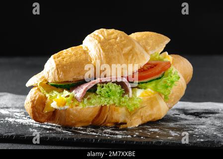 Croissant-Sandwich mit Wurst auf dunklem Hintergrund Stockfoto