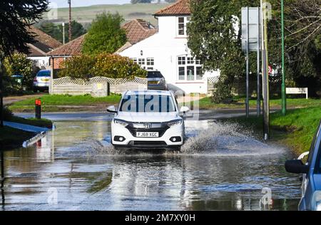 Worthing UK 11. . Januar 2023 - Autos fahren durch Überschwemmungen in Sea Lane , Ferring in der Nähe von Worthing , während sich unruhigeres, feuchtes Wetter im gesamten Vereinigten Königreich ausbreitet : Credit Simon Dack / Alamy Live News Stockfoto