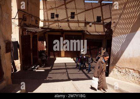 Fez, Marokko-25. April 2014: Gruppe von Personen, die an einem schönen Frühlingsmorgen in der Medina von Fez in einem Hochzeitsladen sitzen und Kunden begrüßen Stockfoto