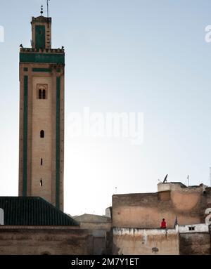 Fez, Marokko-25. April 2014: Sonnenuntergang auf einem Platz, wo Marokkaner Lebensmittel und Kleidung auf einem kleinen Markt verkaufen, viele Leute beobachten und kaufen, andere Restaurants Stockfoto