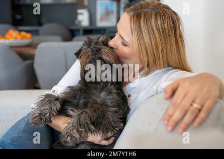 Junge Frau mit ihrem süßen Schnauzer zu Hause. Hübsches Haustier Stockfoto