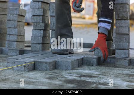 Meister, der graue Betonplatten auf Sandgrundlagen im Hof des Hauses verlegt. Stockfoto