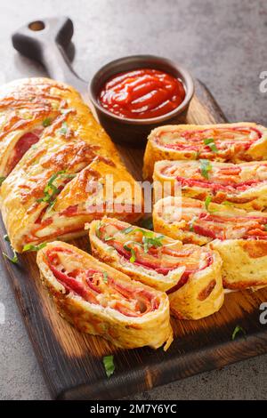 Hausgemachte Stromboli-Pizza mit Käse, Peperoni, Salami auf dem Holzbrett auf dem Tisch. Vertikal Stockfoto