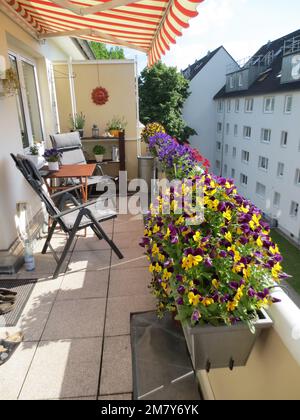 Wunderschöner Balkon mit schwulen Blumen und Sonnenschutz Stockfoto