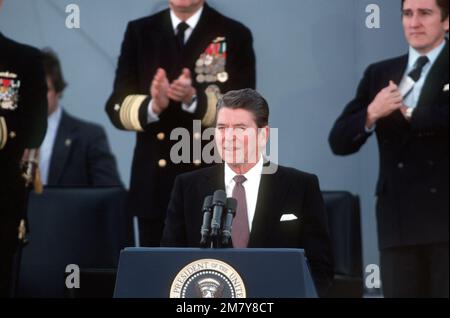 Präsident Ronald Reagan, Hauptredner, spricht zu den Gästen, die an der Wiederinbetriebnahme des Schlachtschiff USS NEW JERSEY (BB-62) teilnehmen. Hinter ihm rechts steht der Marinesoldat John F. Lehman Jr. Basis: Long Beach Naval Shipyard Bundesstaat: Kalifornien (CA) Land: Vereinigte Staaten von Amerika (USA) Stockfoto