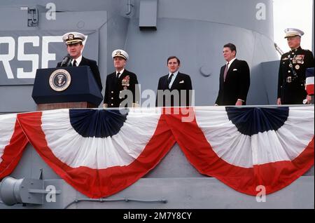 CAPTAIN William M. Fogarty, kommandierender Offizier, spricht während der Wiederinbetriebnahme des Schlachtschiff USS NEW JERSEY (BB-62). Hinter ihm stehen von links nach rechts: Chef der Marineeinsätze ADM James D. Watkins, Marineminister John F. Lehman Jr. und Präsident Ronald Reagan. Basis: Long Beach Naval Shipyard Bundesstaat: Kalifornien (CA) Land: Vereinigte Staaten von Amerika (USA) Stockfoto