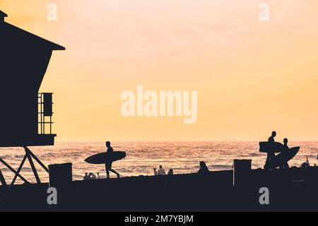 Silhouetten von Surfern am Strand bei Sonnenuntergang in Huntington Beach Stockfoto