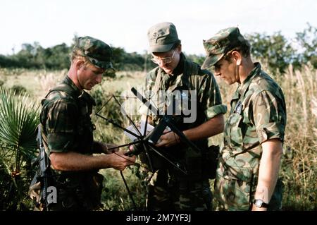 Mitglieder des Kampfkontrollteams (CCT) richteten während der kombinierten US-Honduran-Trainingsoperation „AHUAS TARA“ (GROSSE KIEFER) eine Satellitenantenne in der Nähe einer Abwurfzone ein. Von links nach rechts: SENIOR AIRMAN Libby, 1. Lieutenant Robert Stephan und Master Sergeant Dalton. Betreff Betrieb/Serie: AHUAS TARA (GROSSE KIEFER) Basis: Puerto Lempira Land: Honduras (HND) Stockfoto