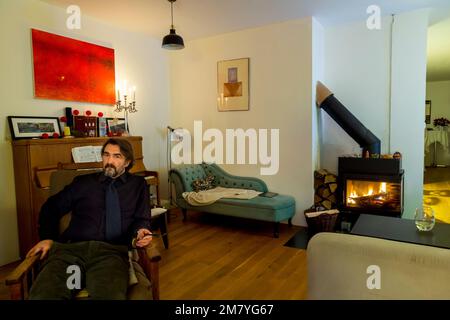 Ein Mann mittleren Alters, der zu Hause auf einem Stuhl sitzt Stockfoto