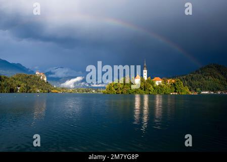 Dramatische Sturmwolken und ein Regenbogen auf dem Bleder See in Slowenien, Europa Stockfoto