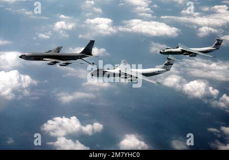 Eine Luft-zu-Luft-Ansicht von links eines KC-135A Stratotanker-Flugzeugs aus dem 97. Bombardement-Flügel, das zwei C-141B Starlifter-Flugzeuge aus dem 437. Military Airlift-Flügel betankt. Land: Unbekannt Stockfoto