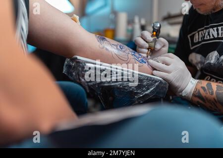 Ein junger Mann bekommt ein frisches Tattoo auf seinem Arm bei einer Tattoo-Konferenz Stockfoto