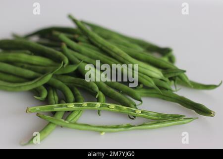 Ein Haufen französische Bohnen, auf weißem Hintergrund mit ein paar Scheiben geschossen. Es wird auch als grüne Bohnen, Buschbohnen, Streichbohnen, Schnappbohnen, Haricot ver bezeichnet Stockfoto