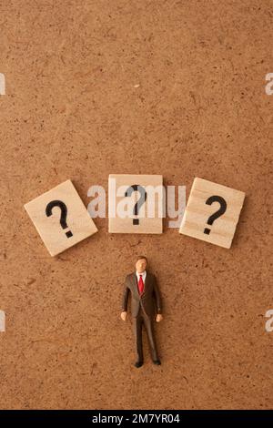 Miniaturfigur mit Fragezeichen um ihn herum Stockfoto