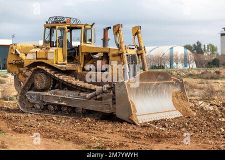 Planierraupe auf der Baustelle. Bulldozer zum Roden, Planieren, Grabenaushub und Graben von Fundamenten. Raupentraktor und Erdbewegung e Stockfoto