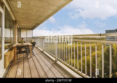 Ein Balkon mit Holzfußboden und weißen Geländern außen, mit Blick auf die Bäume in der Ferne Stockfoto