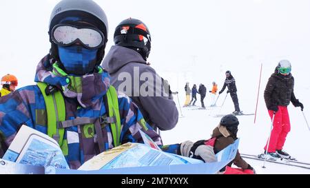 Ein junger Skifahrer überprüft seine Pisten-Karte im Schnee in den 3 Tälern in Frankreich. Stockfoto