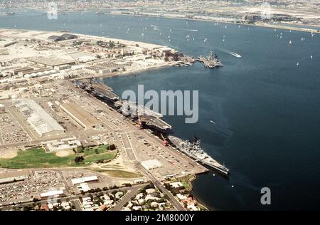 Luftaufnahme von Schiffen der US Navy, die an der Marinestation anlegen. Dabei handelt es sich (im Uhrzeigersinn von unten) um das Schlachtschiff USS NEW JERSEY (BB 62), die Flugzeugträger USS KITTY HAWK (CV 63) und USS RANGER (CV 61), den nuklearbetriebenen geführten Raketenkreuzer USS LONG BEACH (CGN 9) und den geführten Raketenzerstörer USS CHANDLER (DDG 996). Basis: Marineflugstation, Nordinsel Bundesstaat: Kalifornien (CA) Land: Vereinigte Staaten von Amerika (USA) Stockfoto