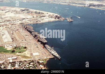 Luftaufnahme von Schiffen der US Navy, die an der Marinestation anlegen. Dabei handelt es sich (im Uhrzeigersinn von unten) um das Schlachtschiff USS NEW JERSEY (BB 62), die Flugzeugträger USS KITTY HAWK (CV 63) und USS RANGER (CV 61), den nuklearbetriebenen geführten Raketenkreuzer USS LONG BEACH (CGN 9) und den geführten Raketenzerstörer USS CHANDLER (DDG 996). Basis: Marineflugstation, Nordinsel Bundesstaat: Kalifornien (CA) Land: Vereinigte Staaten von Amerika (USA) Stockfoto