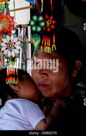 Indigene Frau mit Kunsthandwerk, die ihre Tochter im Vordergrund trägt Stockfoto