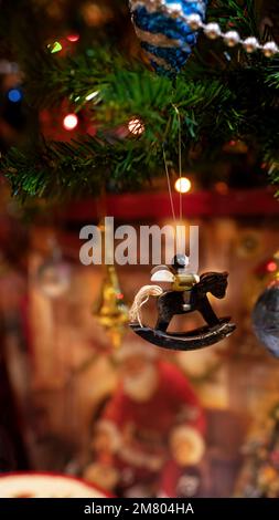 Eine alte Weihnachtsbaumdekoration. Ein hölzerner Engel sitzt auf einem Schaukelpferd mit einem Schwanz aus Garnsträngen. Stockfoto