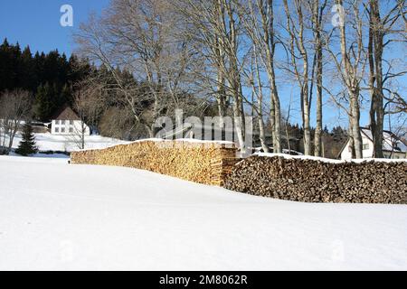 Landschaftsszene im Winter mit neuen und alten Holzstapeln in einer Reihe Stockfoto