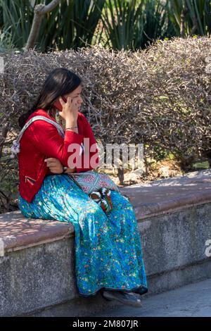 Eine Frau, die am Telefon spricht, in einem traditionellen Kostüm der wixarika huichol-Kultur Stockfoto