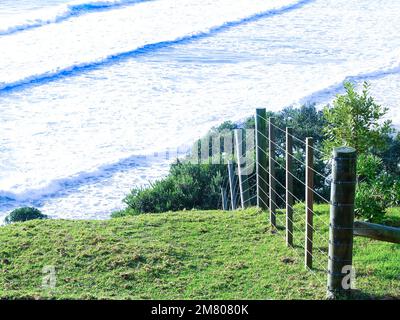 Meeresschaum auf Wellen, die unter dem Hügelkamm auf dem Mount Maunganui Rollen. Stockfoto