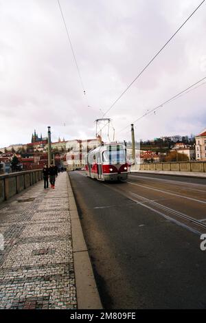 Ein vertikales Bild der Menschen, die am Nachmittag entlang der Männerbrücke in Prag, Tschechische Republik, mit der Straßenbahn vorbeifahren Stockfoto