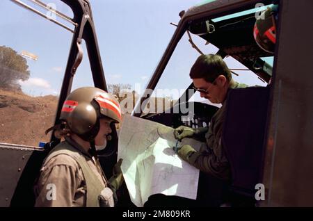 SPEZIALIST 4 Leslie J. Fellhoelter, eine von drei weiblichen Crewchefs, die dem 25. Kampfluftfahrtbataillon, Kompanie B, 25. Infanterieabteilung, zugeteilt sind, konsultiert eine Karte mit DEM CHEFKRIEGEROFFIZIER 3 Robert A. Stroud, Pilot ihres UH-1-Hubschraubers. Sie nehmen am jährlichen Armeeausbildungs- und Evaluierungsprogramm (ARTEP) ihrer Einheit im US Army Pohakuloa Training Area Teil. Bundesstaat: Hawaii (HI) Land: Vereinigte Staaten von Amerika (USA) Stockfoto