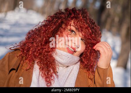 Porträt einer lächelnden, kubigen, rothaarigen Frau auf einem Winterspaziergang. Stockfoto