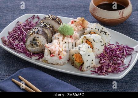Sushi-Stücke auf einem Teller mit Essstäbchen mit Essstäbchen und Soja. Stockfoto