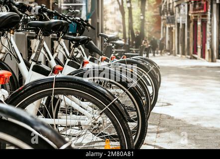 Rückseite der weißen Elektrofahrräder, die auf dem Dock geparkt sind. Konzept der nachhaltigen Mobilität in der Stadt. Stockfoto