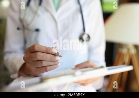 Weibliche Ärztin, die mit medizinischen Formularen und Dokumenten arbeitet, Nahaufnahme. Stockfoto